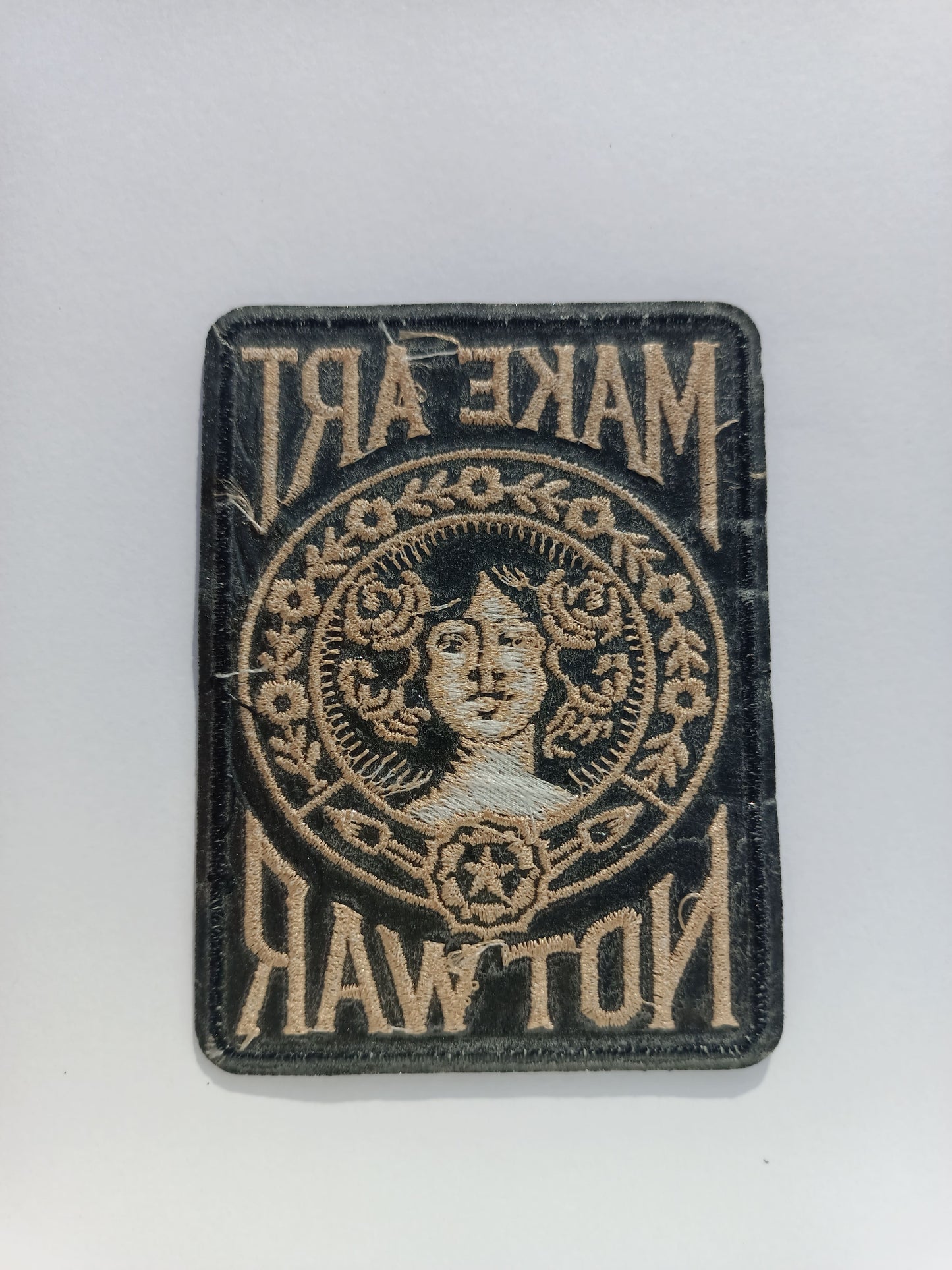 Parte trasera parche bordado estilo vintage con tipografía retro y motivos florales alrededor de un rostro femenino.