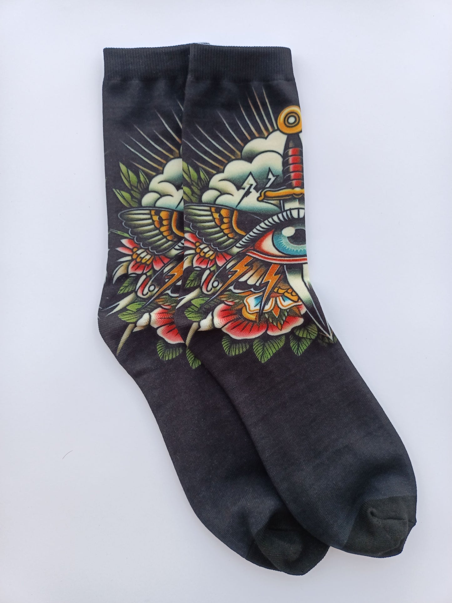 Calcetines negros con diseño de tatuaje tradicional que muestra una daga atravesando un ojo con rosas rojas y hojas verdes.
