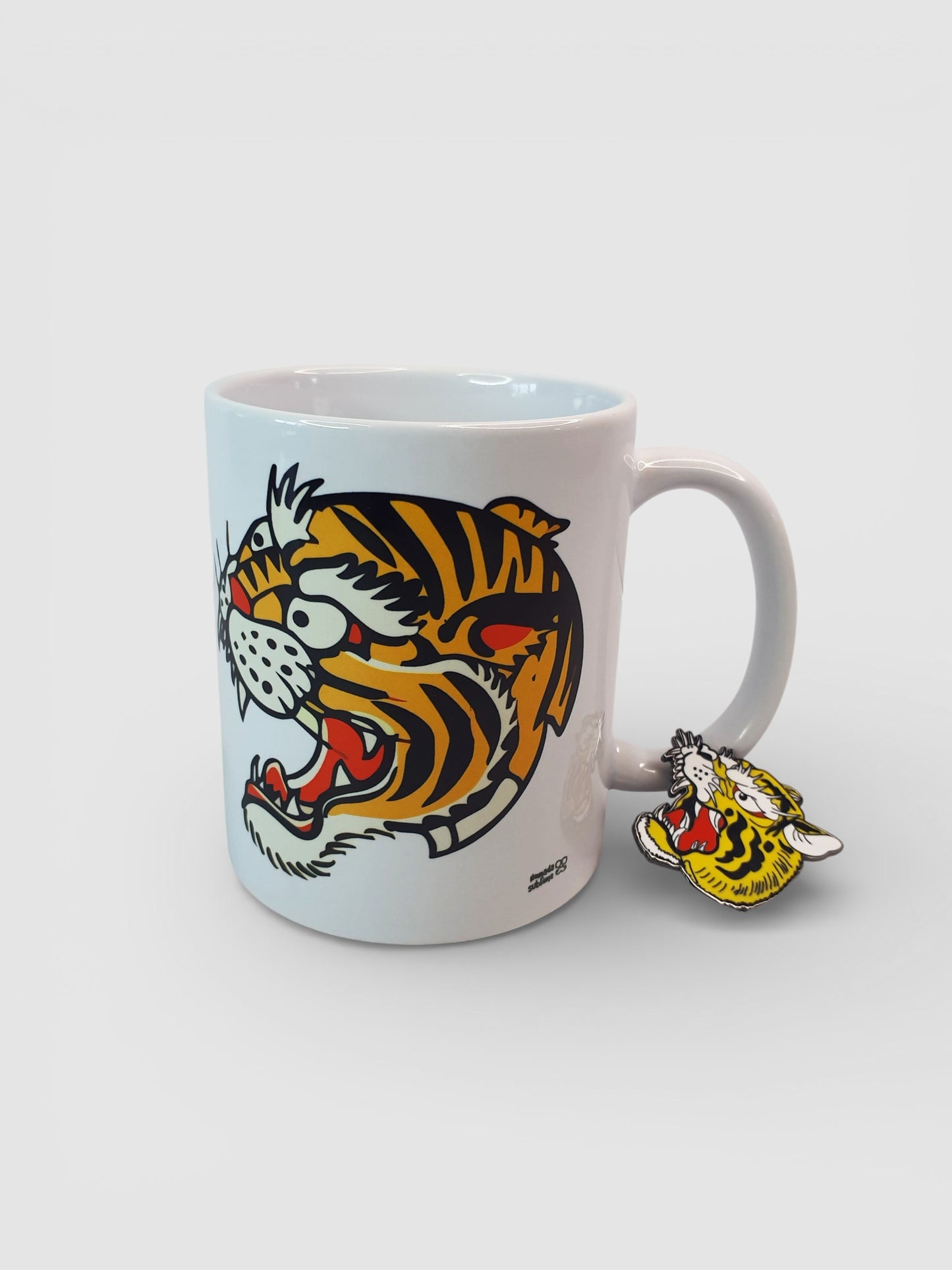 "Pack de taza y pin con diseño de tigre estilo old school, inspirado en tatuajes tradicionales, en colores vibrantes y trazos perfectos."