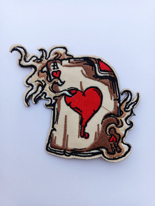 Parche bordado carta con corazón rojo estilo tatuaje old school sobre fondo blanco.