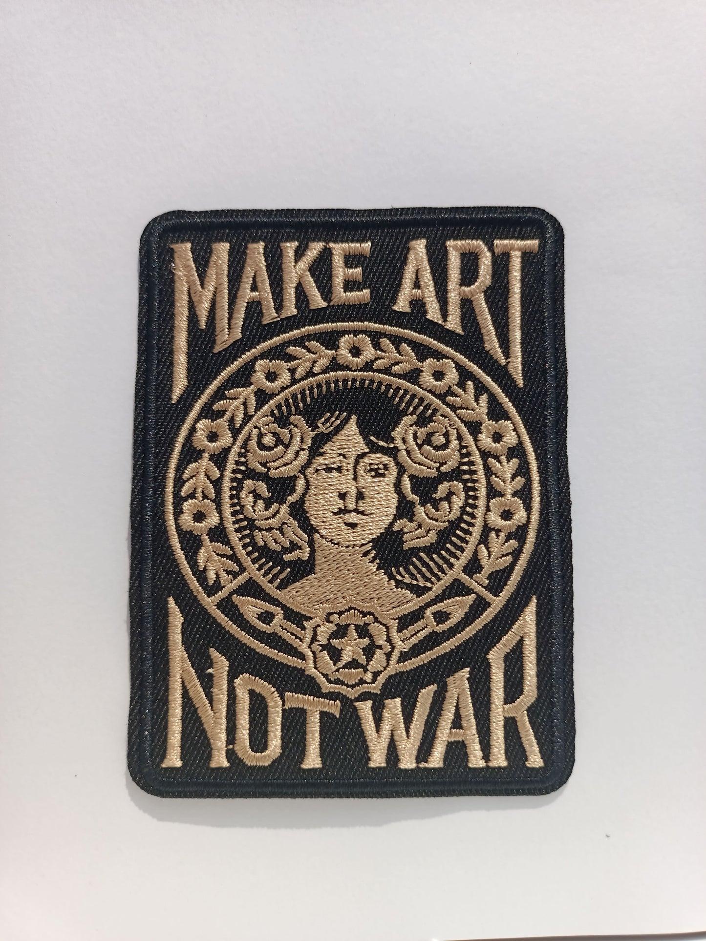 Parche Tattoo rectangular en negro con la icónica frase Make Art Not War y diseño gráfico clásico bordado.