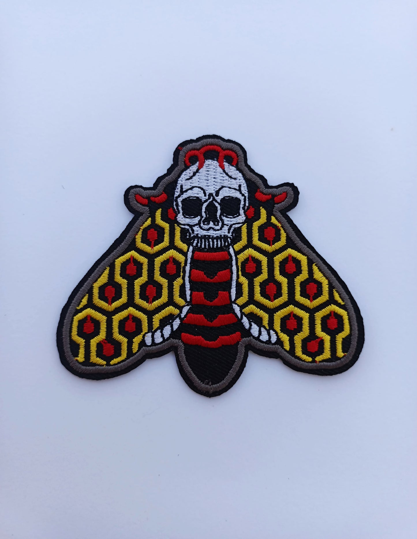 Parche decorativo con ilustración de polilla en bordado clásico, estilo old school tatuaje americano tradicional.