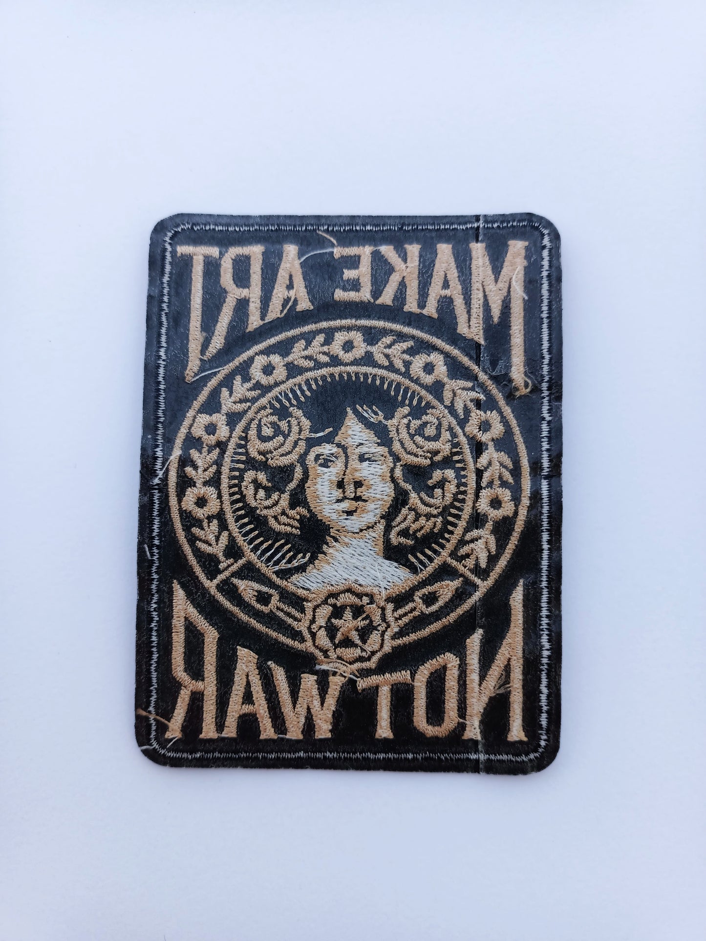 Parte trasera pegamento parche bordado estilo vintage con tipografía retro y motivos florales alrededor de un rostro femenino.