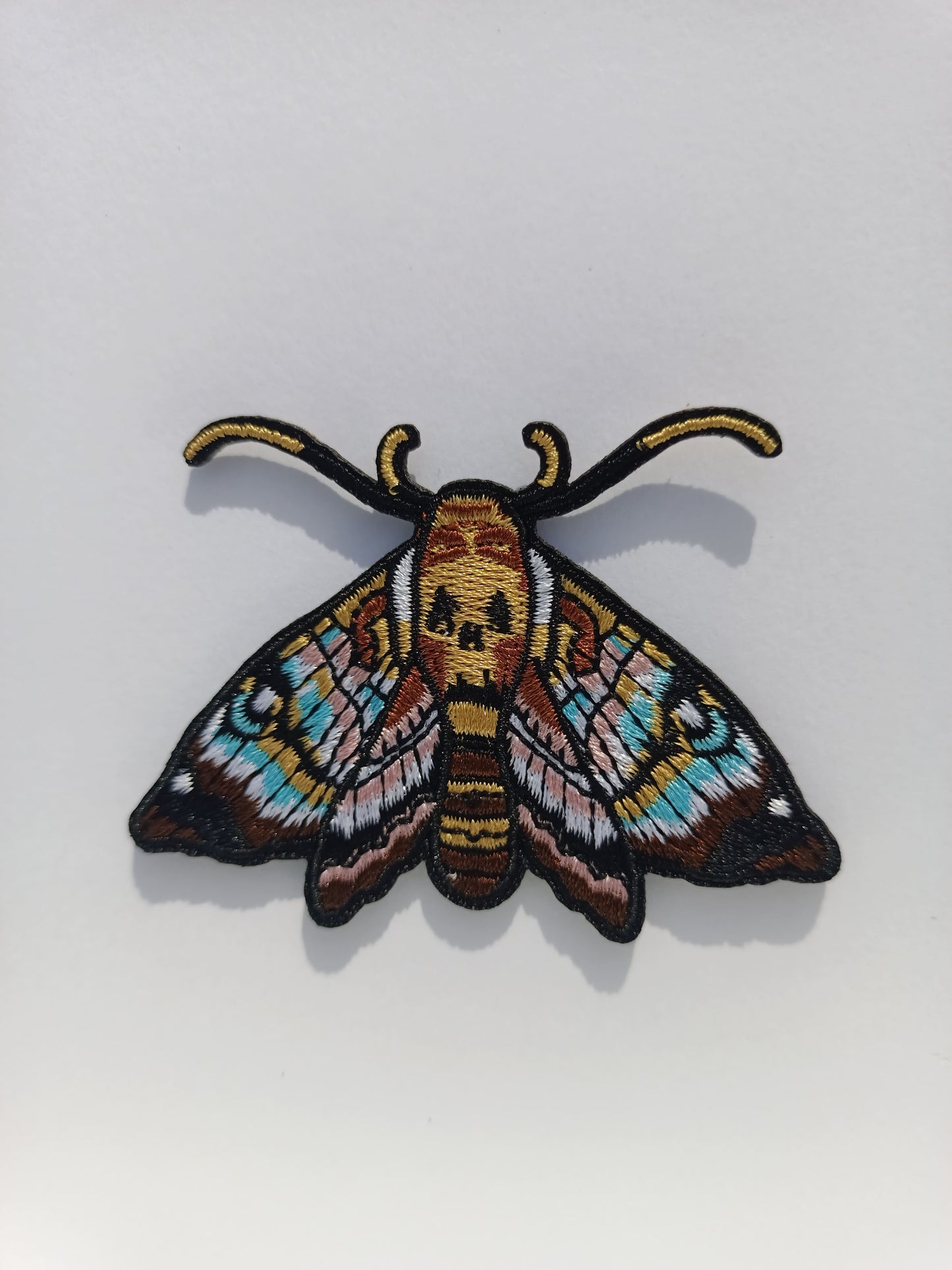 Parche bordado de polilla con diseño inspirado en el tatuaje. Colores vivos y líneas limpias.