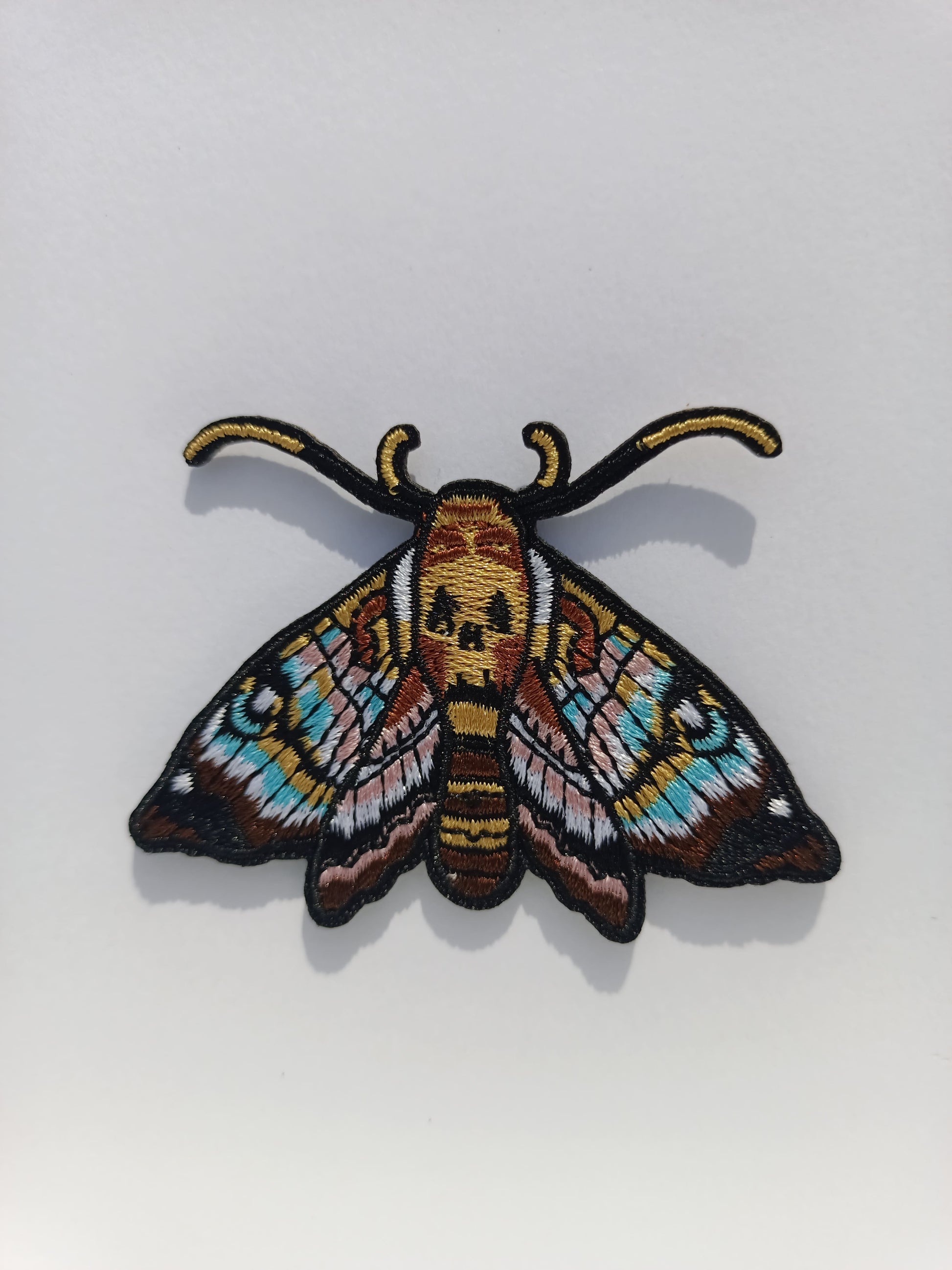 Parche bordado de polilla con diseño inspirado en el tatuaje. Colores vivos y líneas limpias.