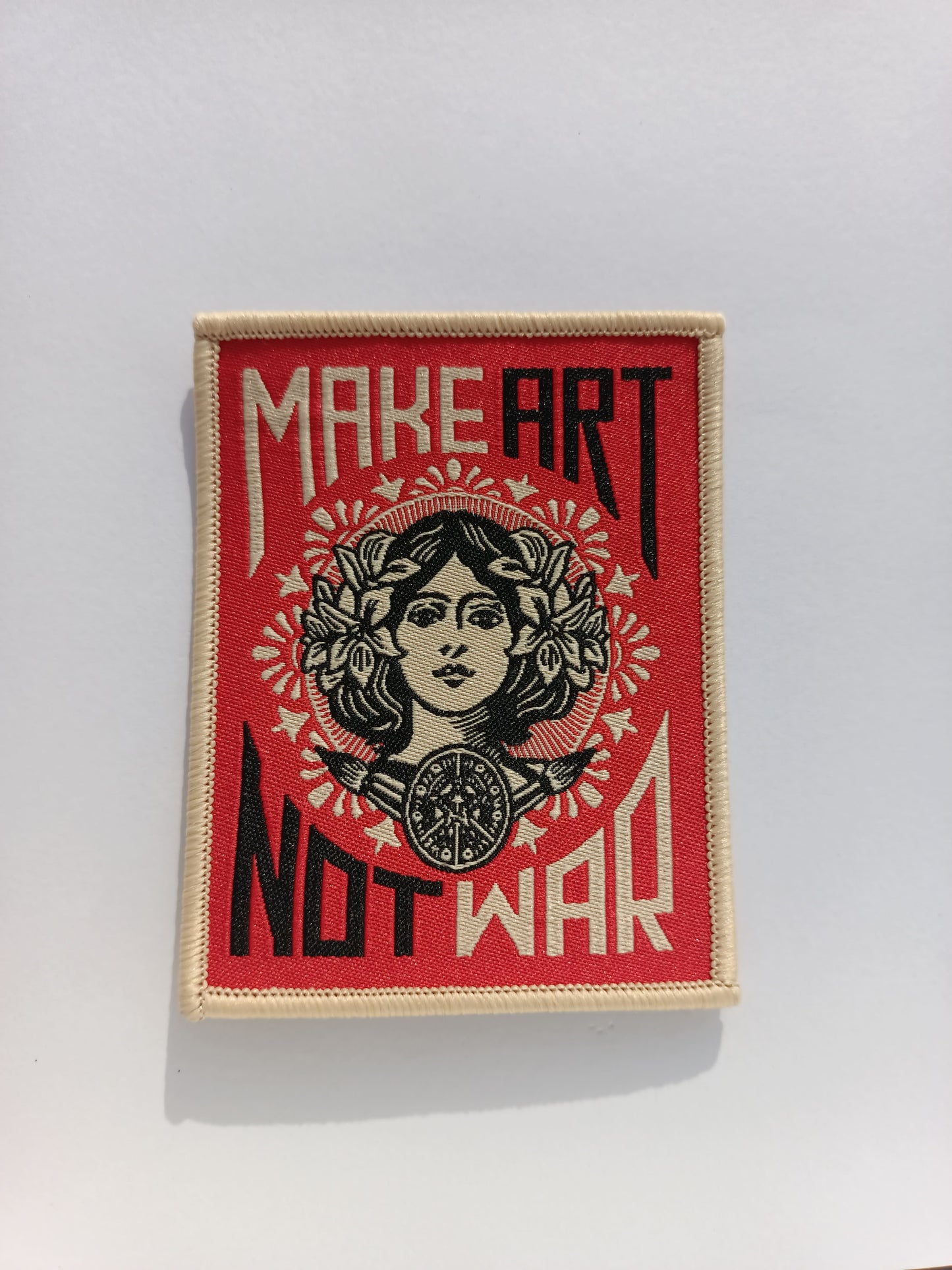 Parche bordado estilo vieja escuela con la frase “MAKE ART NOT WAR” en letras vintage y con detalles retro.