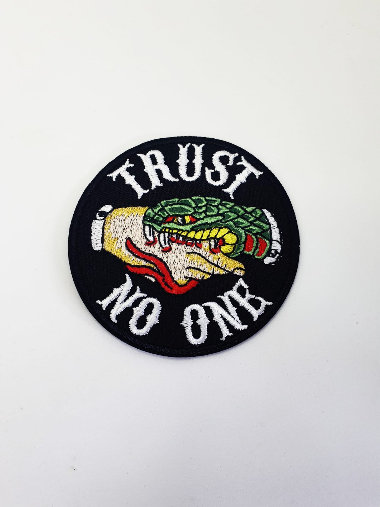 Parche bordado circular con mensaje rebelde Trust No One y motivos inspirados en tatuaje tradicional.