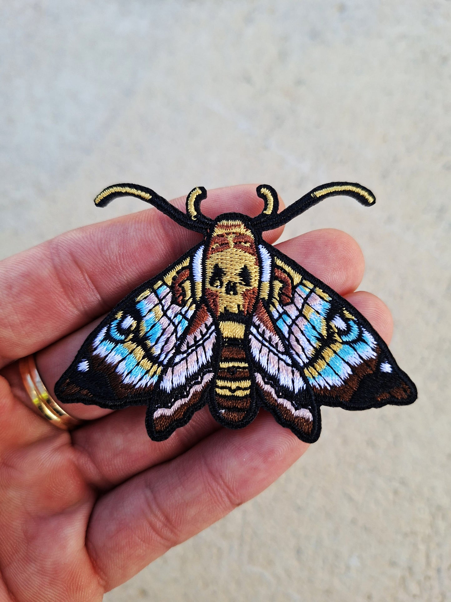 Parche bordado de polilla estilo tatuaje old school con líneas clásicas y colores intensos.