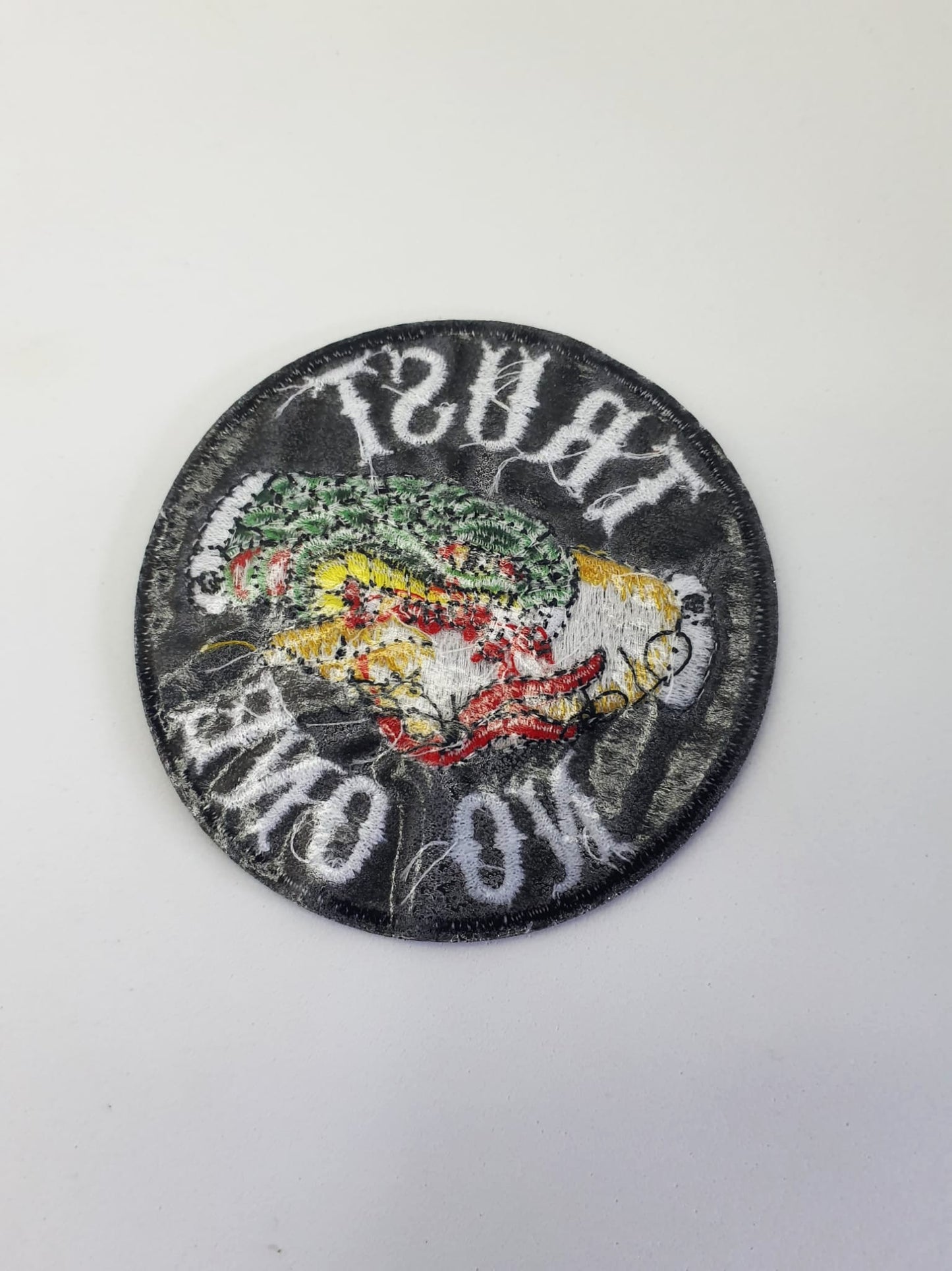 Parte trasera parche circular con frase Trust No One y diseño de mano mordida por una serpiente estilo Old School.