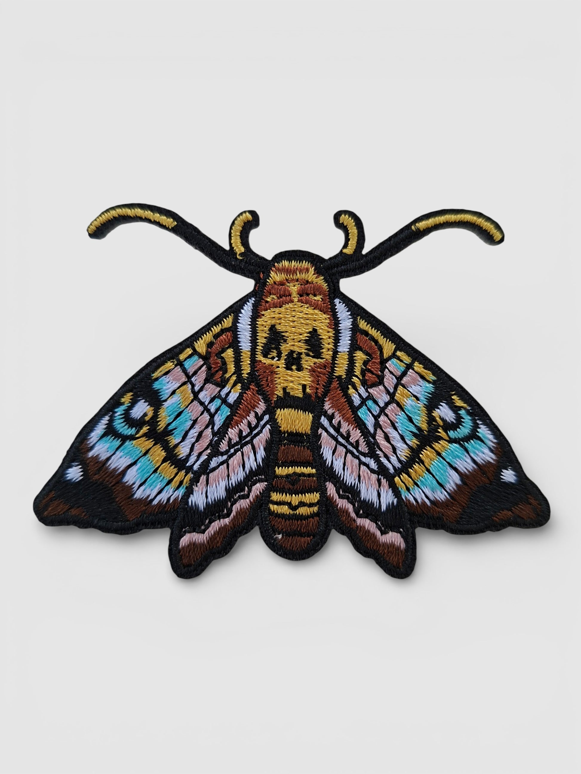 Parche bordado de polilla con diseño inspirado en el arte del tatuaje. Colores vivos y líneas definidas.