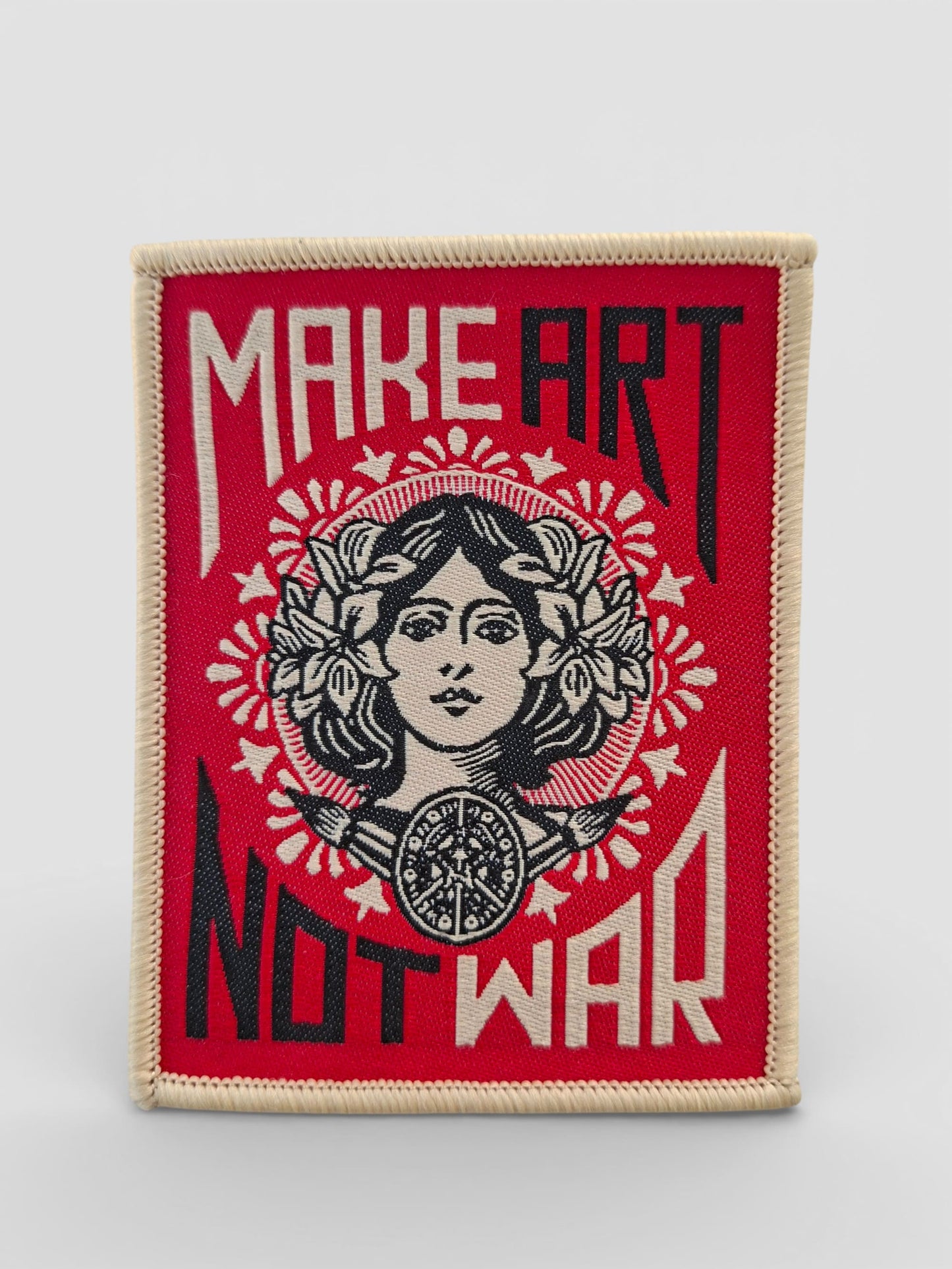 Parche bordado tradicional estilo old school con la frase “MAKE ART NOT WAR” en letras vintage y con detalles atemporales.