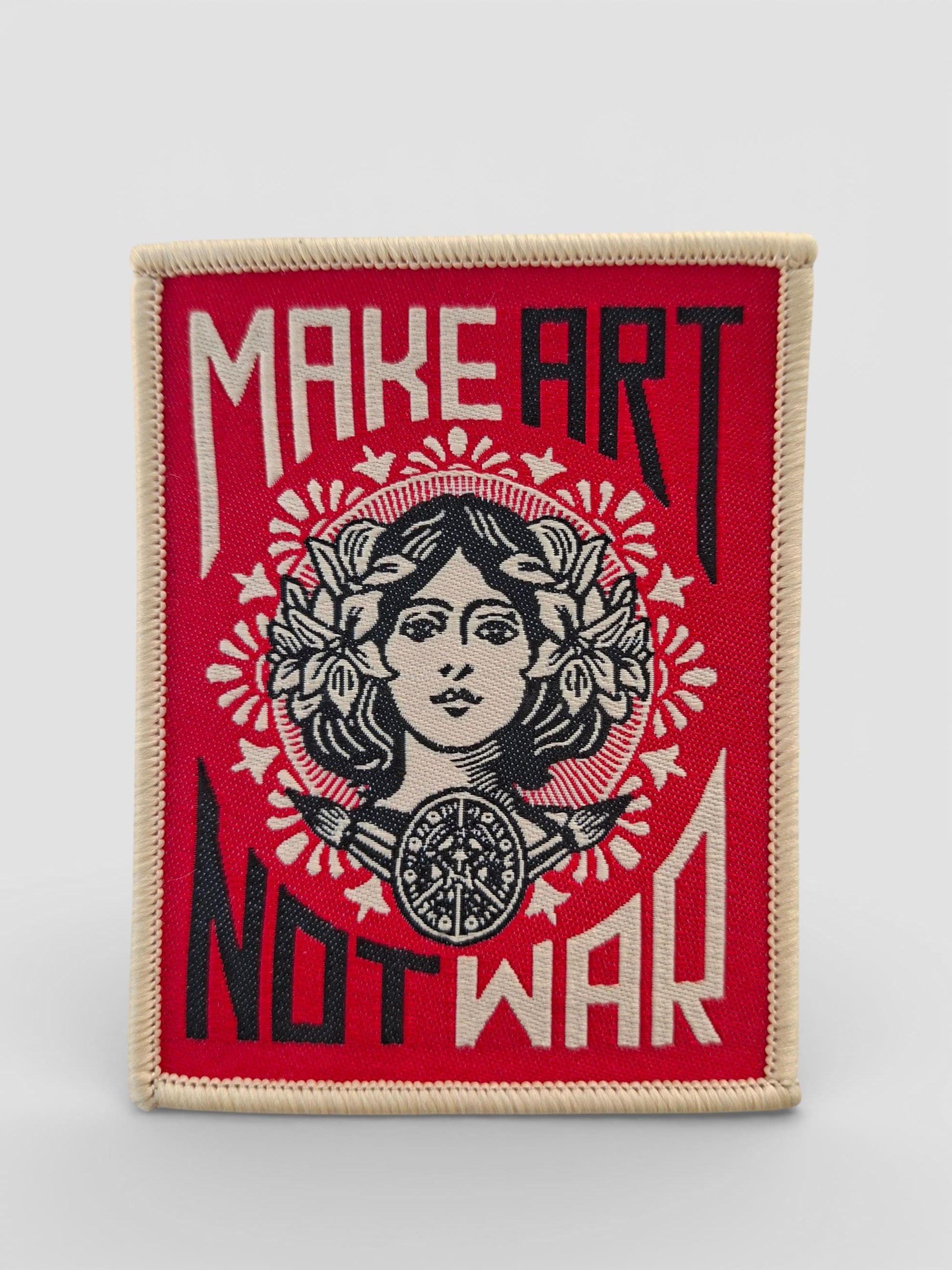 Parche bordado tradicional estilo old school con la frase “MAKE ART NOT WAR” en letras vintage y con detalles atemporales.