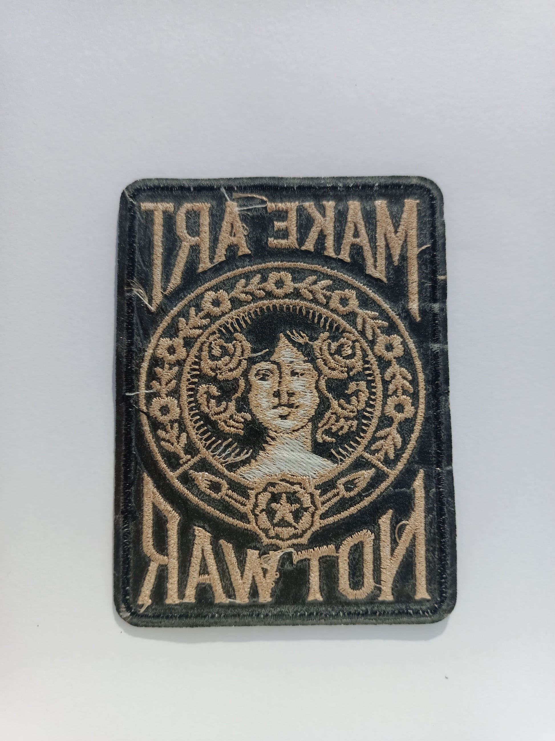 Parte trasera parche bordado estilo vintage con tipografía retro y motivos florales alrededor de un rostro femenino.