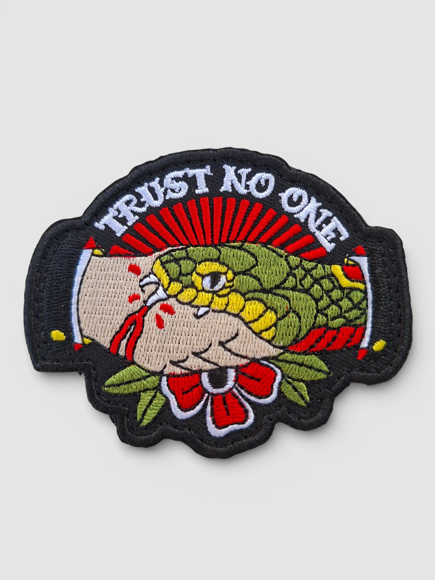 Detalle bordado parche Trust No One con serpiente y mano, el icónico diseño clásico americano.