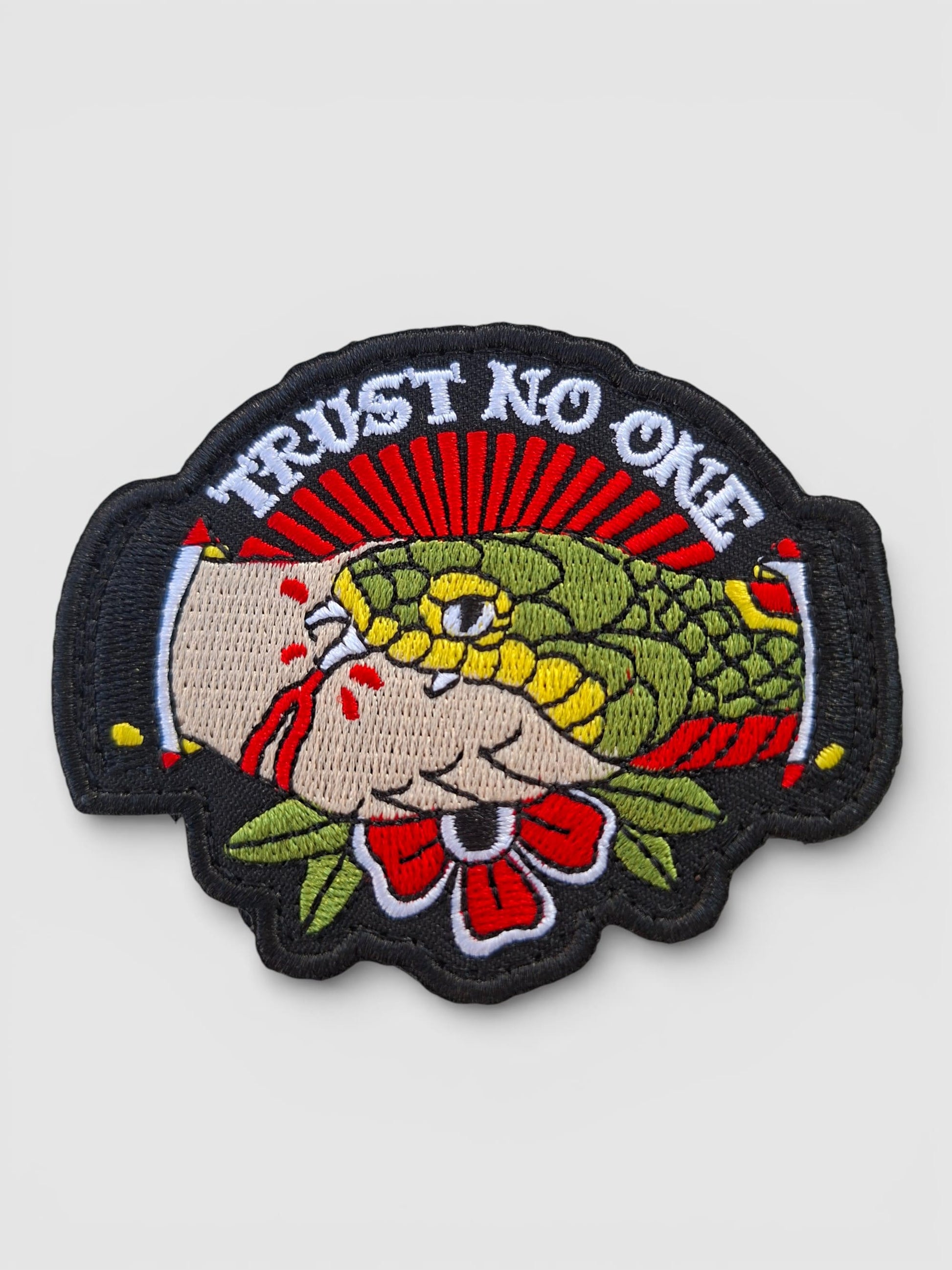 Detalle bordado parche Trust No One con serpiente y mano, el icónico diseño clásico americano.