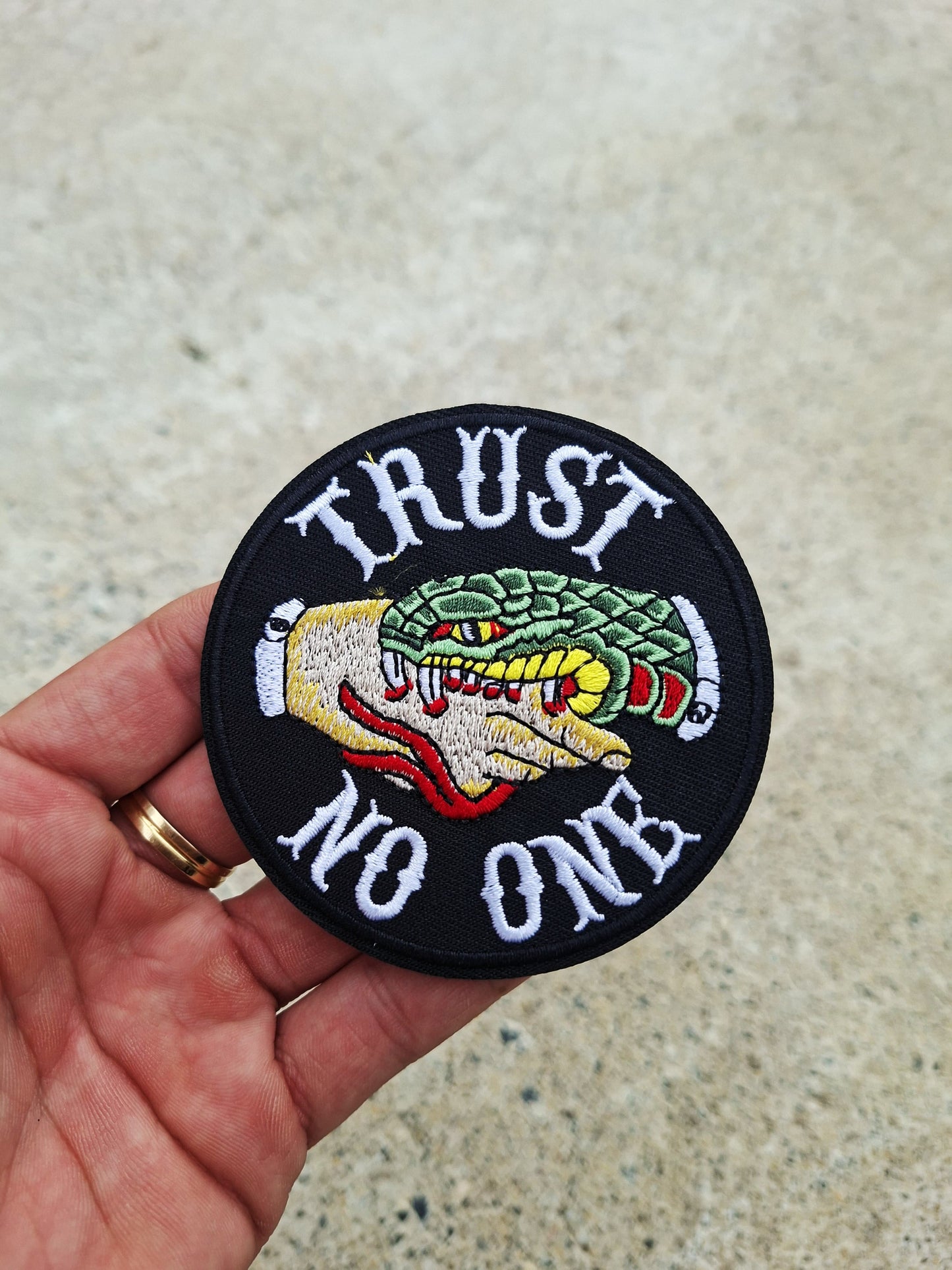 Parche bordado circular con mensaje rebelde Trust No One y motivos inspirados en tatuaje tradicional.