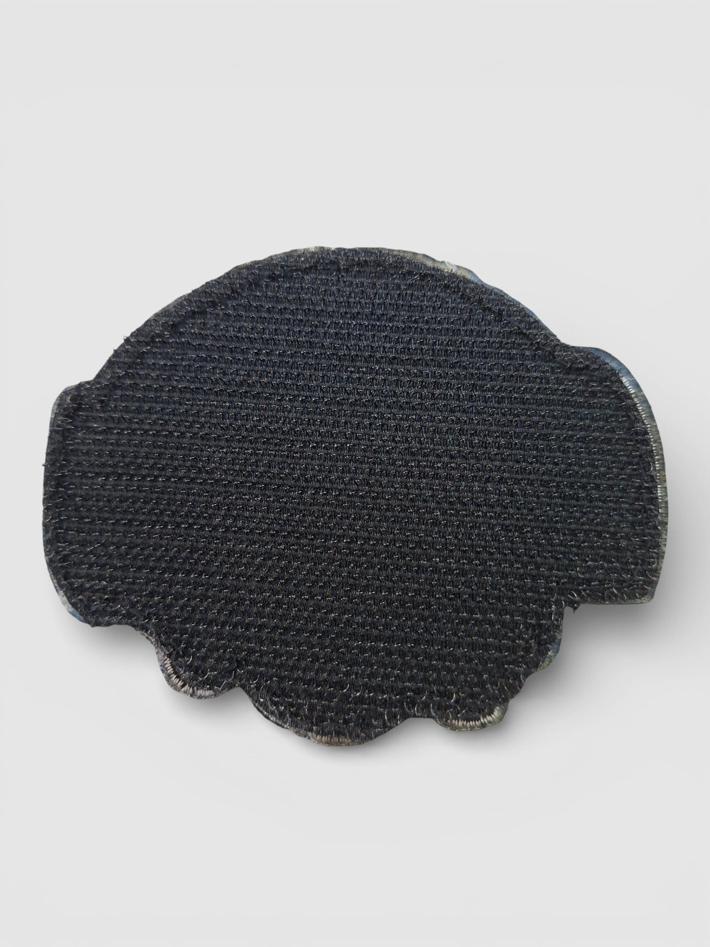 Parte trasera del parche Trust No One, base textil y acabado limpio se adhiere con velcro.