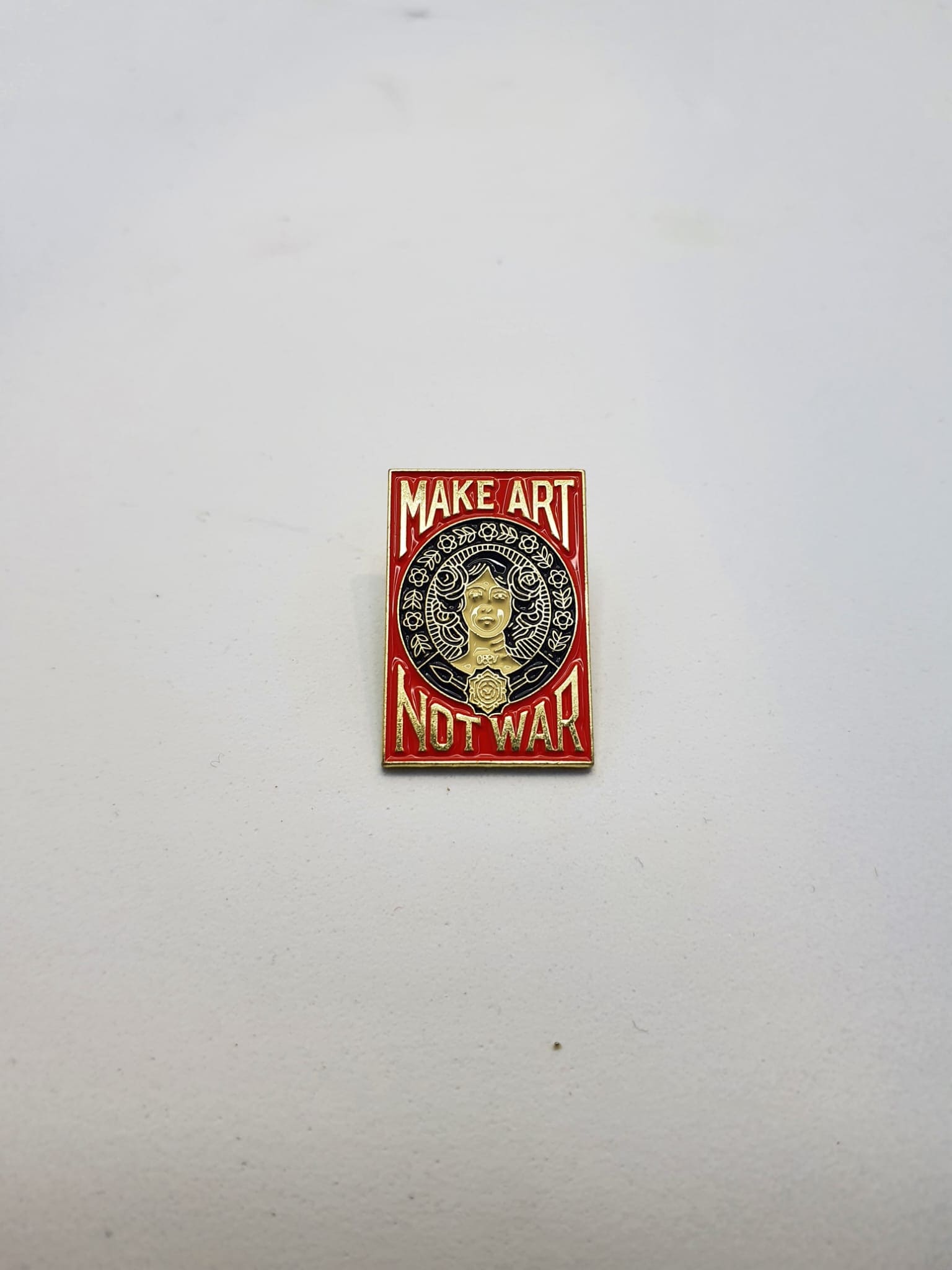 Pin estilo Old School – Haz Arte No Guerra, rojo y dorado.