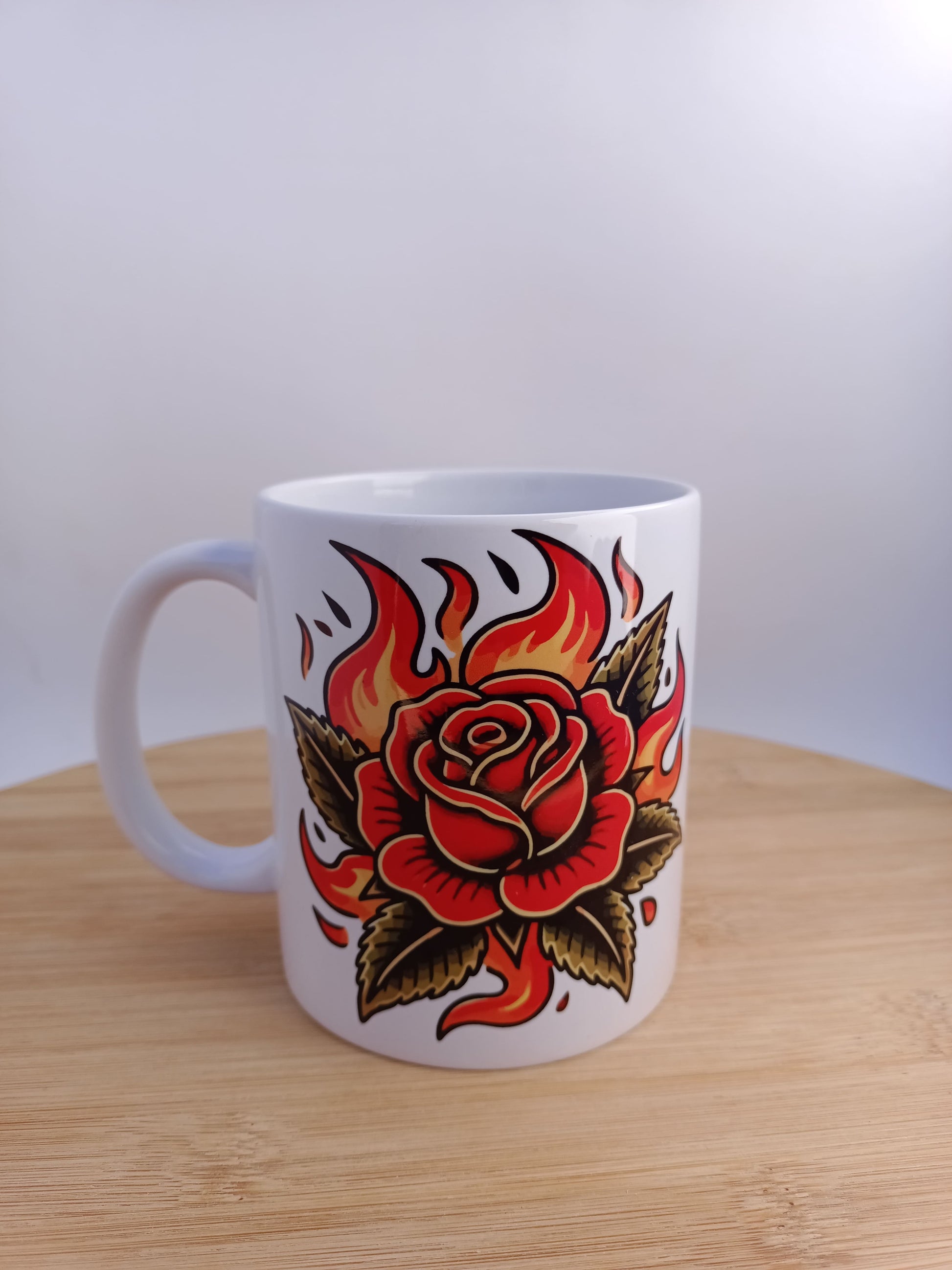 Taza con rosa tradicional en llamas estilo tattoo old school, ilustración vintage clásica.