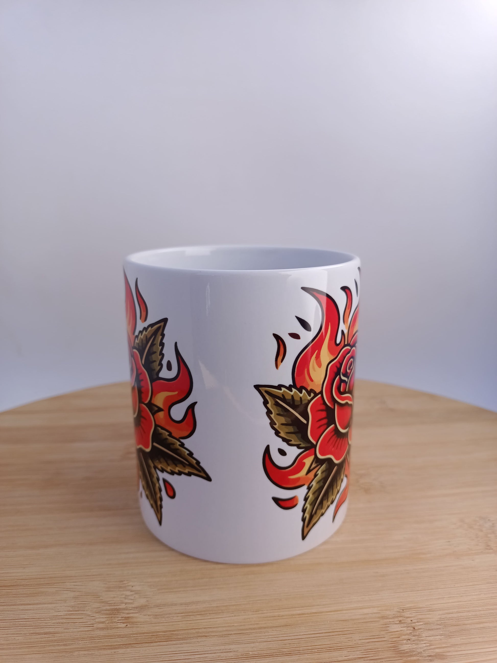 "Taza de cerámica con rosa en llamas old school, diseño de tatuaje tradicional ideal para amantes del arte retro."