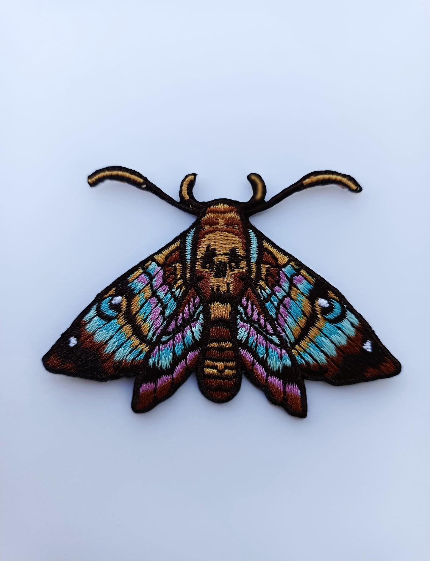 Parche bordado de mariposa con diseño inspirado en tatuaje. Colores vivos y líneas limpias.